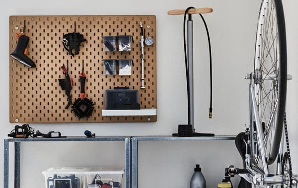 Metal shelves and a peg board create balcony storage. A bike pump sits on the shelves and a bike is hanging on the wall.