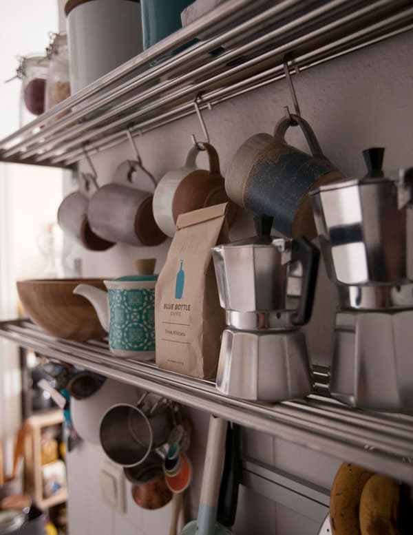 Metal shelves with rails with lots of options for storing kitchen essentials like mugs and coffee makers.