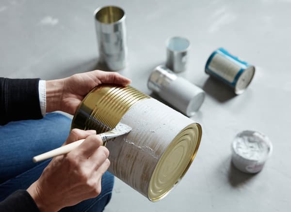 Metalldosen werden mit Zementfarbe bemalt, um als Aufbewahrung auf der Arbeitsplatte ein neues Leben zu bekommen.