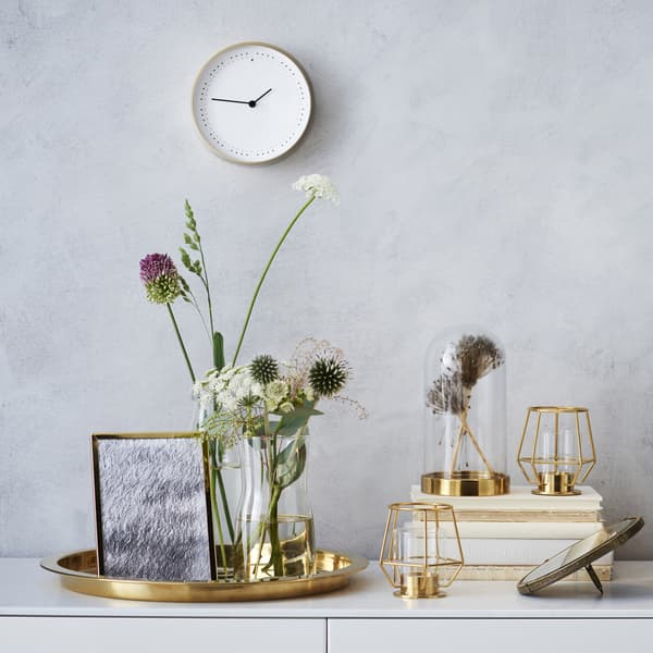 Metallic home accessories and a flower arrangement on top of a white unit.
