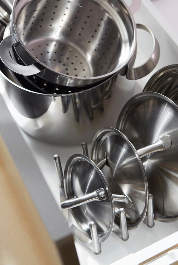 Metallic jars and their lids neatly stacked in an open kitchen drawer.
