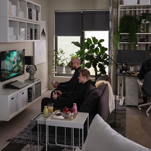 Męzczyzna grający z synem na telewizorze  w pokoju dziennym z półkami serii KALLAX.