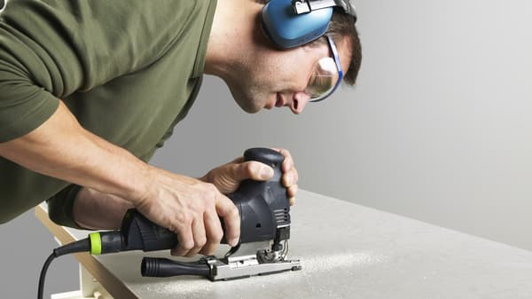 Mężczyzna w słuchawkach wycina blat.