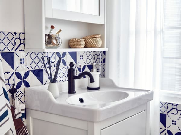 مغسلة حمام بيضاء HEMNES/RÄTTVIKEN من ايكيا مع أدراج تغلق بسلاسة، في حمام ببلاطات أزرق وأبيض.