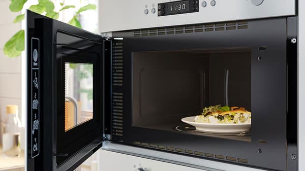 Micro-onde en inox ouvert avec un plat à l'intérieur
