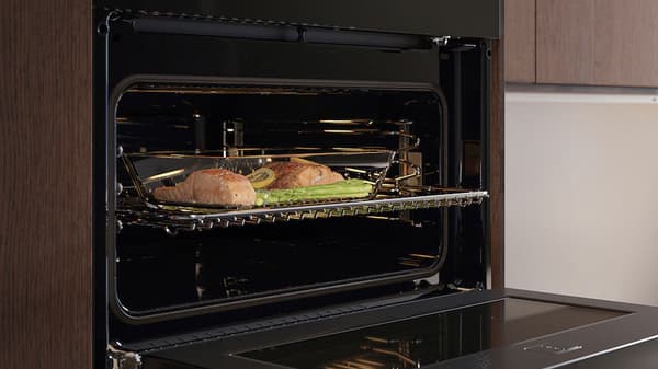 Micro-onde noir ouvert avec une grille et un plat de poissons 
