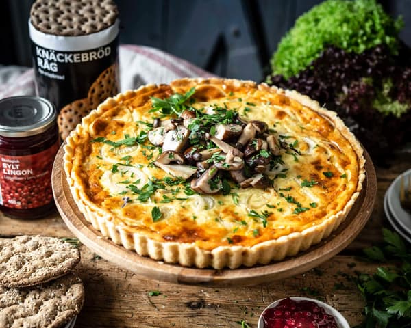 Midsommar Quiche mit Pilz Topping auf einer Kuchenplatte.