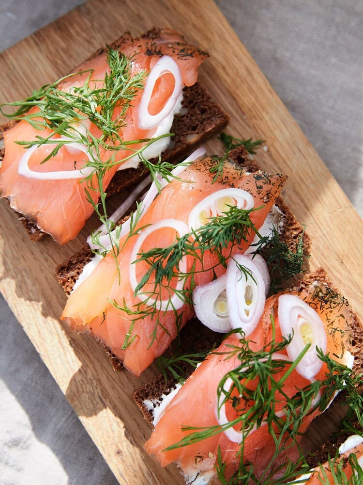 Midsummer food in the form of salmon sandwiches on a chopping board.