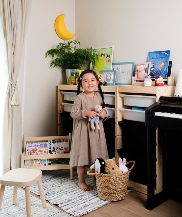 ภาพของลูกสาวของ Mieko ยืนอยู่ข้างที่เก็บของเล่นของเธอในห้องนั่งเล่น