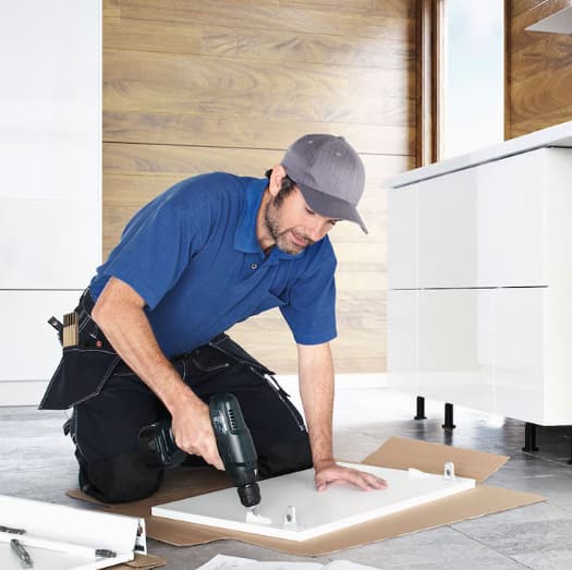 Mies poraa valkoista levyä polvillaan lattialla.