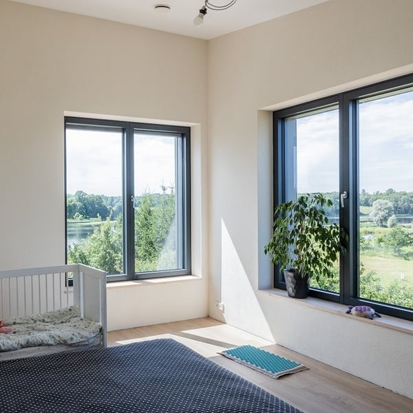Minimalist bedroom interior with large windows, baby crib, and scenic nature view