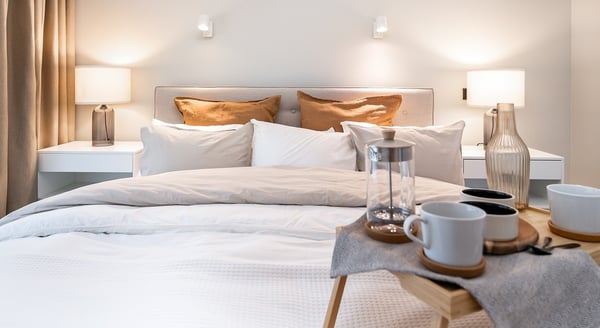 Minimalist bedroom with double bed, beige pillows and bedside lamps