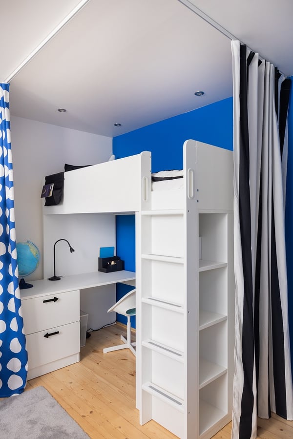 Minimalist children’s desk setup with white chair, task lamp, and blue wall background