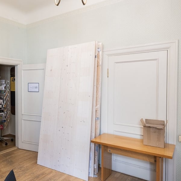 Minimalist interior with stacked wooden panels, work table, and renovation materials