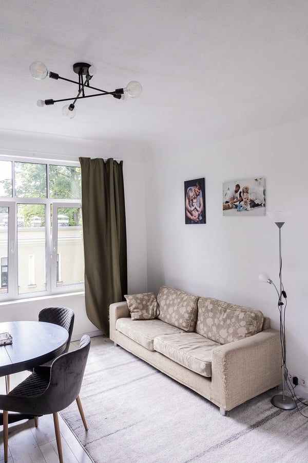 Minimalist living room with beige sofa, dining table, large window, and modern ceiling light