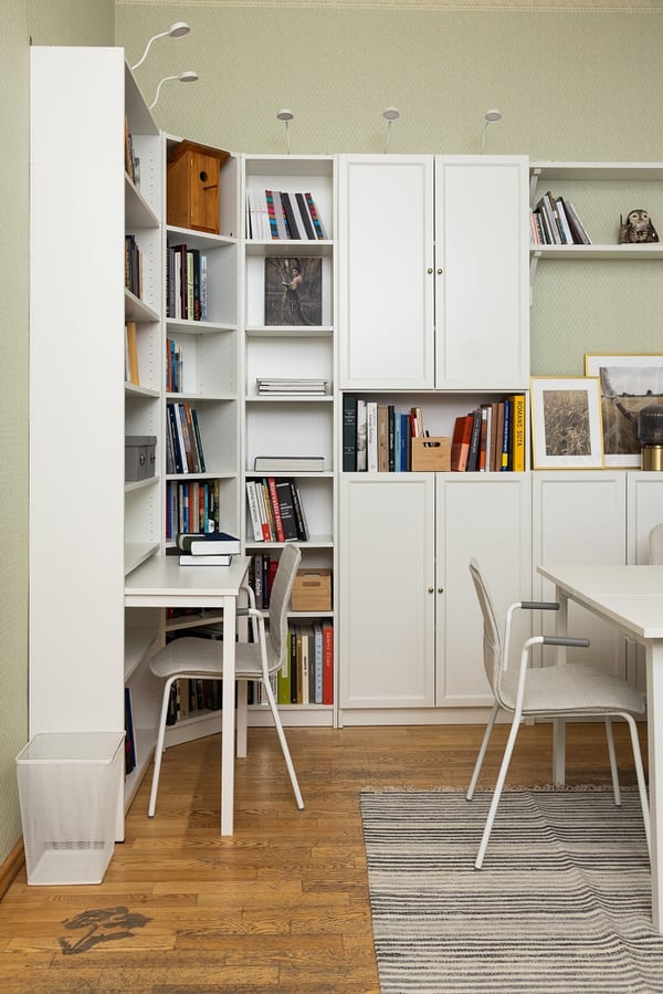 Minimalist study area with white furniture, bookshelves, and wooden floor