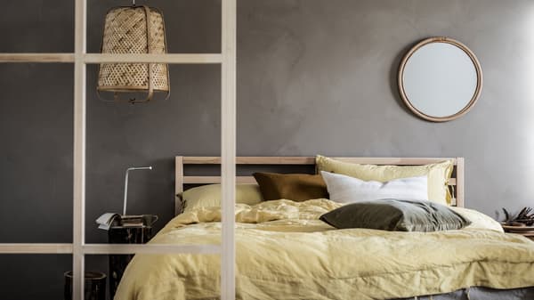 Minimalistic bedroom with grey walls and toned-down colour scheme, wood details, a TARVA double bed, and a KNIXHULT lamp.