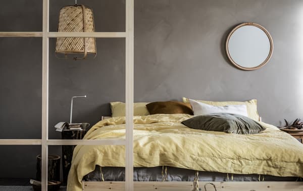 Minimalistic bedroom with grey walls and toned-down colour scheme, wood details, a NEIDEN double bed, and a KNIXHULT lamp.