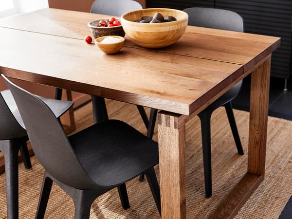 厚みのある木製テーブルに黒いチェアを合わせたモダンダイニング。ラグと観葉植物で温かみを演出。