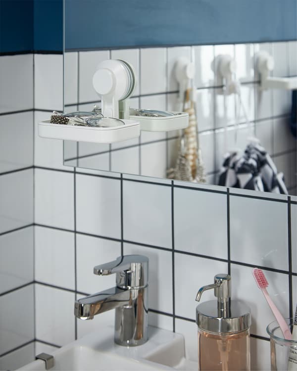Mirror cabinet, a white soap dish with a suction cup on it, a chrome-plated mixer tap, and a soap dispenser in chrome-effect.