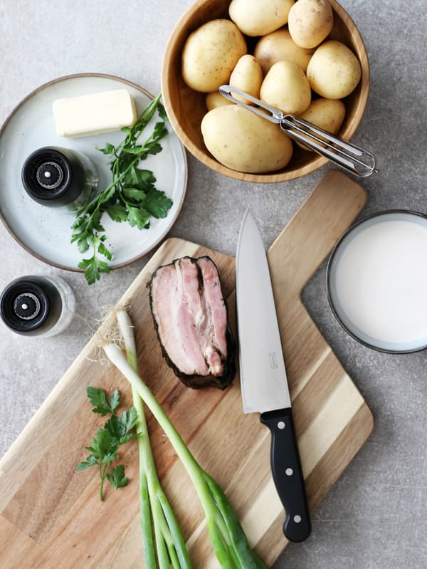 Misa so zemiakmi a dezertný tanier GLADELIG s kúskom masla, petržlenovou vňaťou a mlynčekom na korenie IKEA 365+ IHÄRDIG vedľa dosky SMÅÄTA.