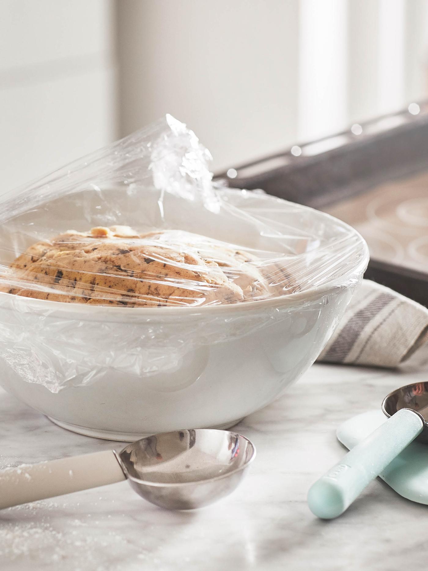 Mísa těsta přikrytého fólií, za ní leží forma na pečení HEMMABAK, v popředí leží dvě odměrky LÄTTBAKAD.