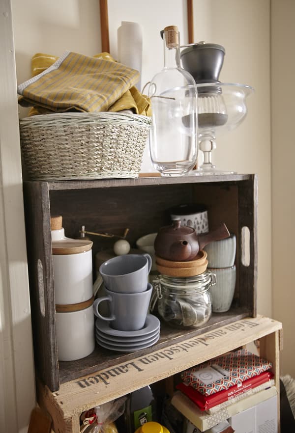 Mismatched mugs and dishware are stored in a wooden crate for a vintage feel in this kitchen.
