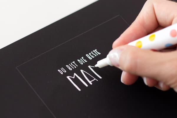 Mit einem weißen deckenden Stift wird der Abdruck der Vorlage nachgeschrieben. 