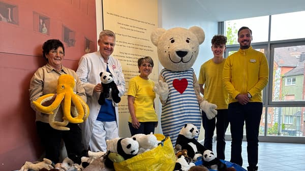 Mitarbeitende von IKEA Kamen und der „Klinik für Kinder- und Jugendmedizin des Ev. Krankenhauses Hamm“ stehen gemeinsam mit dem Maskottchen „FABLER BJÖRN“ vor einem großen Haufen gespendeter Kuscheltiere. Zu sehen sind unter anderem Pandas und ein gelber Stoff-Oktopus. Die Übergabe fand im April 2025 im Rahmen einer Spendenaktion statt.
