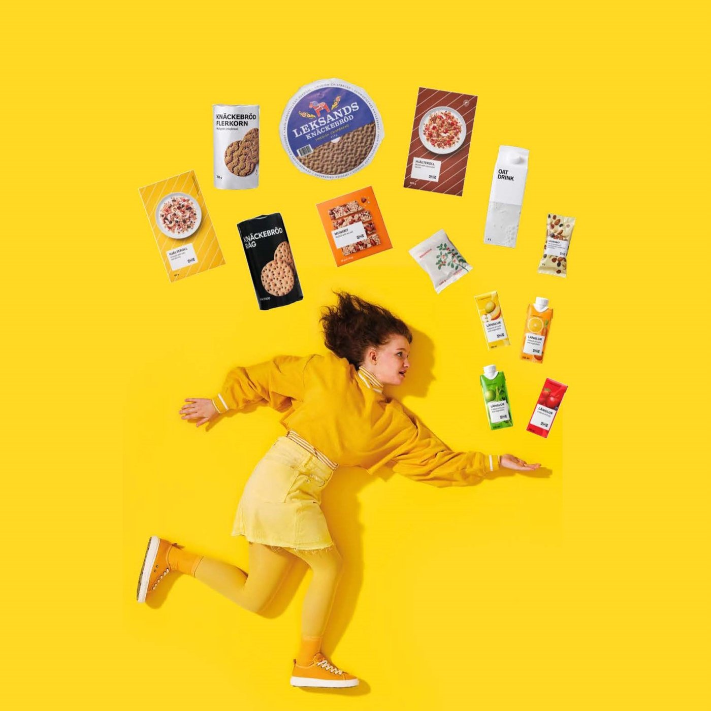 Mladá dívka běžící ve žlutém běžící na žlutém pozadí vyhazující výrobky IKEA nad sebe