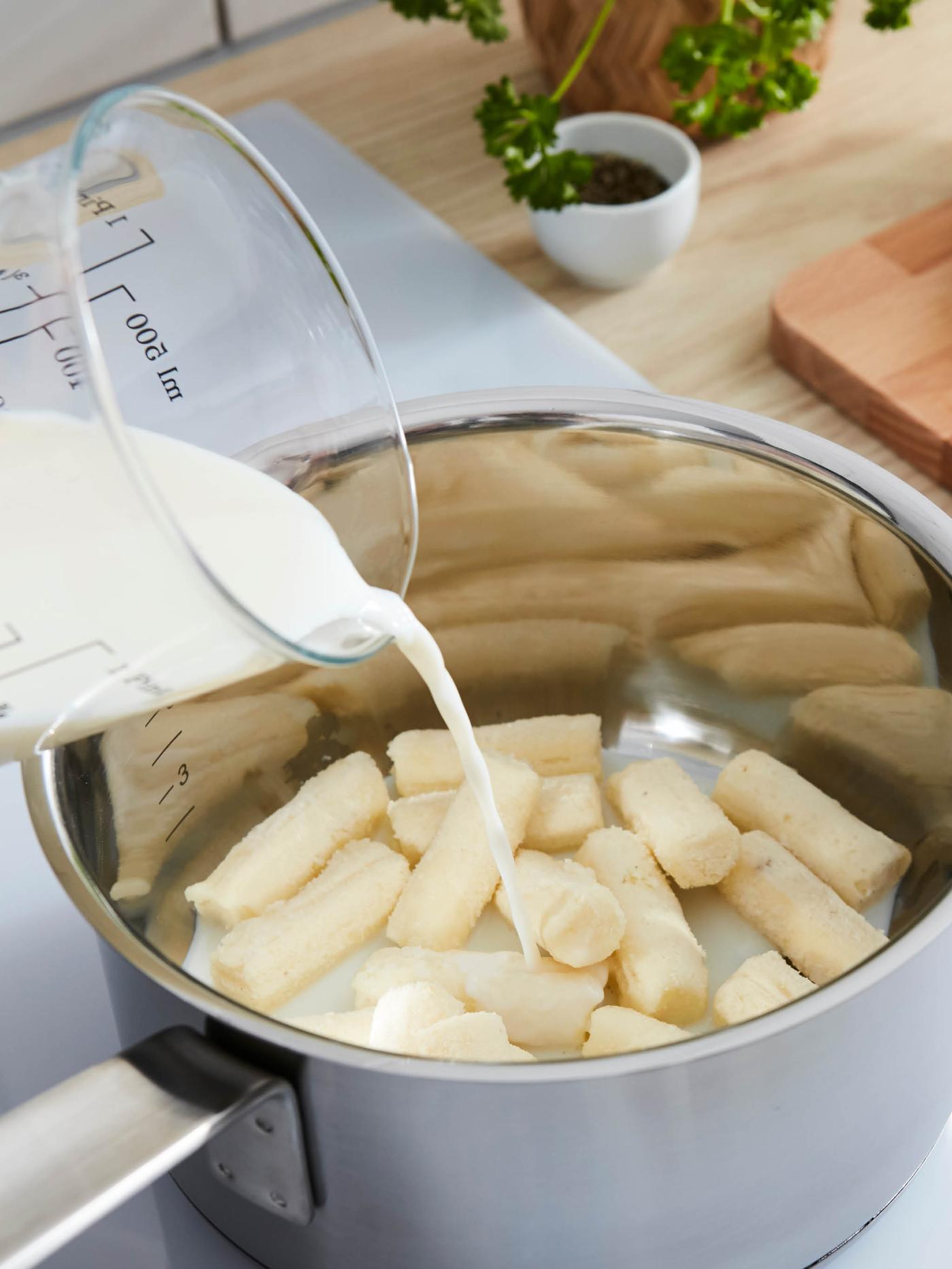 Mléko z odměrky VARDAGEN teče do rendlíku s válečky bramborové kaše ALLEMANSRÄTTEN.