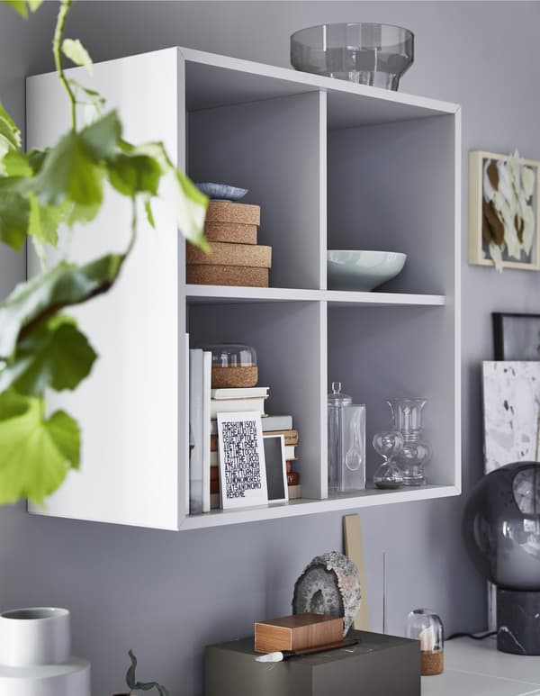 Mobile da parete EKET a forma di cubo con oggetti decorativi all'interno con libri, ciotole e altri oggetti.