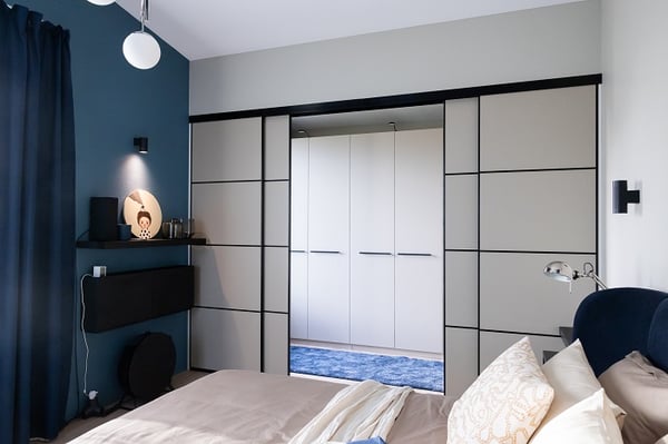 Modern bedroom with sliding wardrobe doors, blue accent wall, and minimalist design