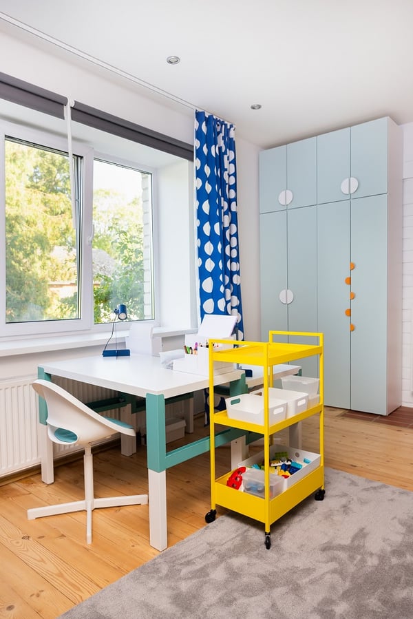 Modern bunk bed with integrated desk, ladder, shelving, and blue accent wall in kids room