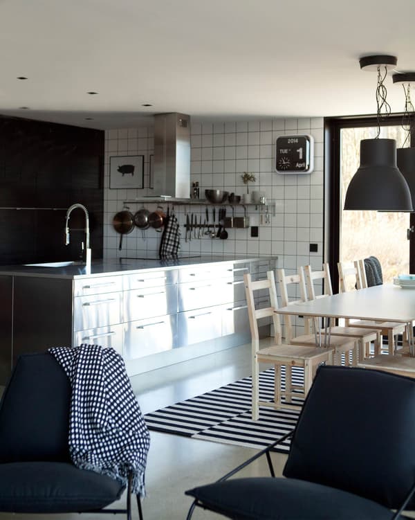 Modern design brings a dramatic metal kitchen island together with open storage, white tiles and dark accents.