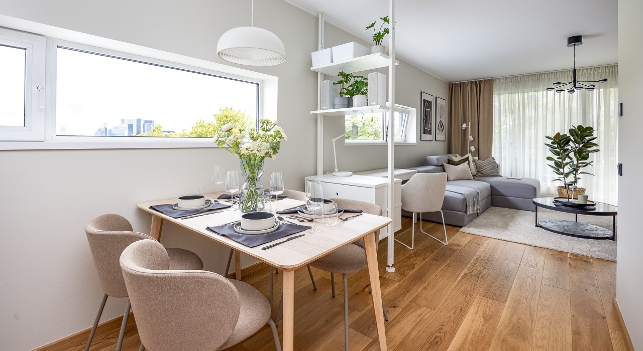 Modern dining area with light wood table and beige chairs near window.