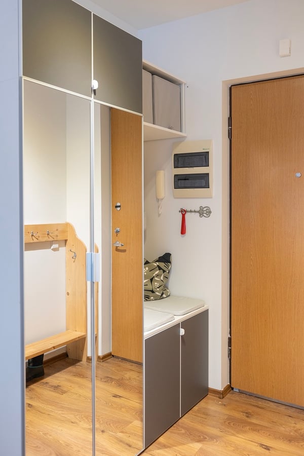 Modern hallway with mirrored wardrobe and bench with cushion.