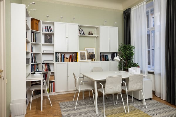 Modern home office with white bookcases, desk, and organized storage