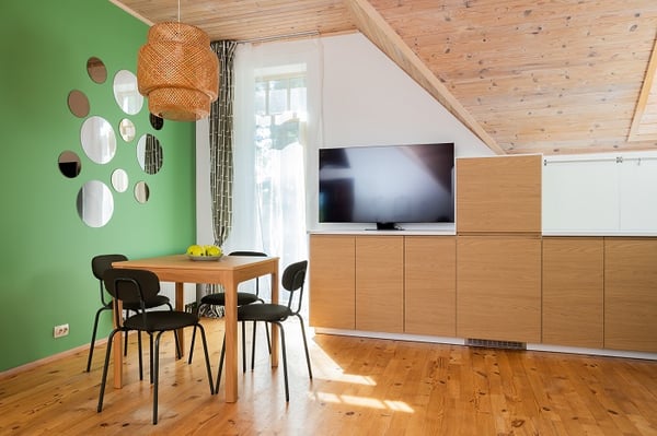 Modern kitchen and dining area with green accent wall, wooden furniture, and TV