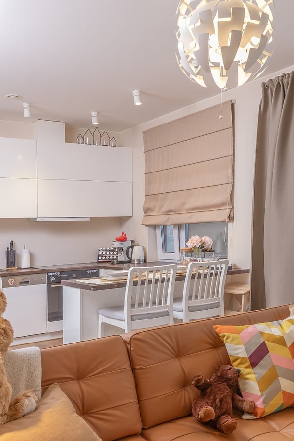 Modern kitchen with white cabinets, bar counter, and pendant lamp.