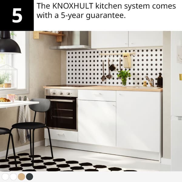 Modern kitchen with white cabinets, wood countertop, oven, polka dot backsplash, plant and black-white rug.