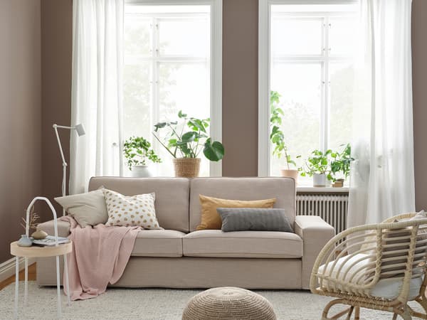 Modern KIVIK sofa with soft pillows and white curtains in the living room.