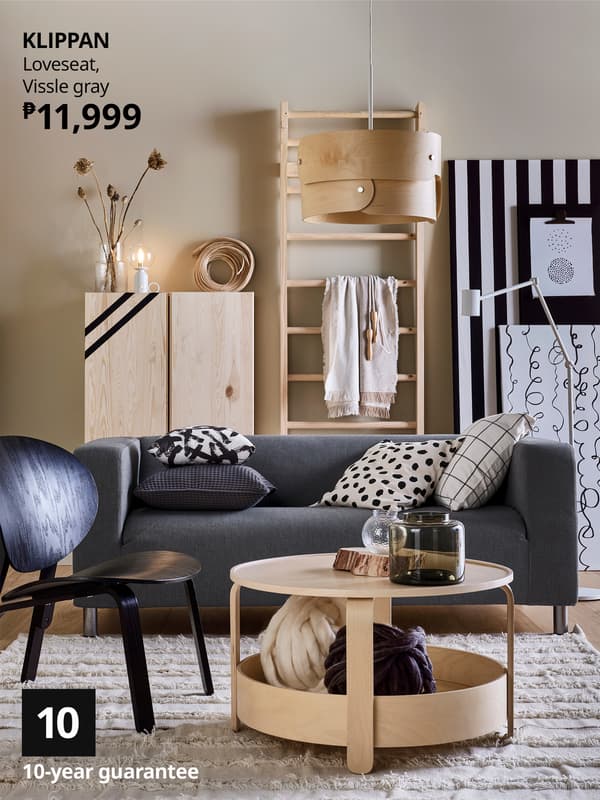 Modern living room featuring a gray KLIPPAN loveseat, wooden decor, round coffee table, and stylish lighting, priced at ₱11,999.
