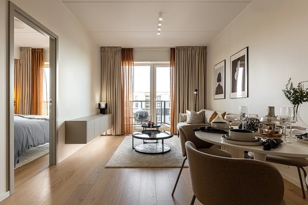 Modern open-plan living room with dining area, sofa, and balcony access.