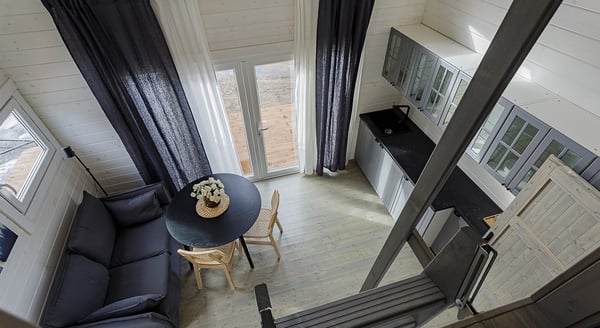 Modern tiny house interior with kitchenette, dining table, and loft access