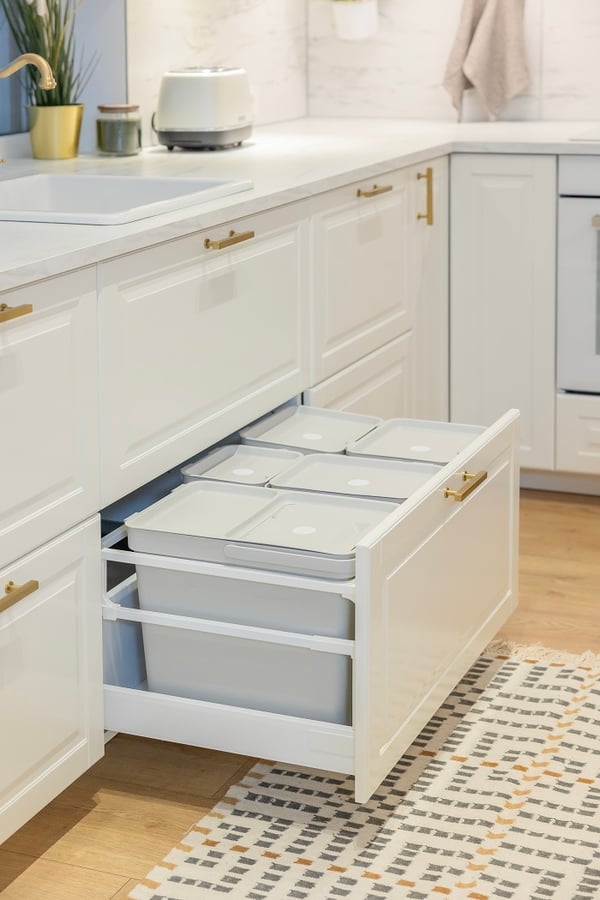 Modern white kitchen drawer with built-in waste sorting bins under countertop.
