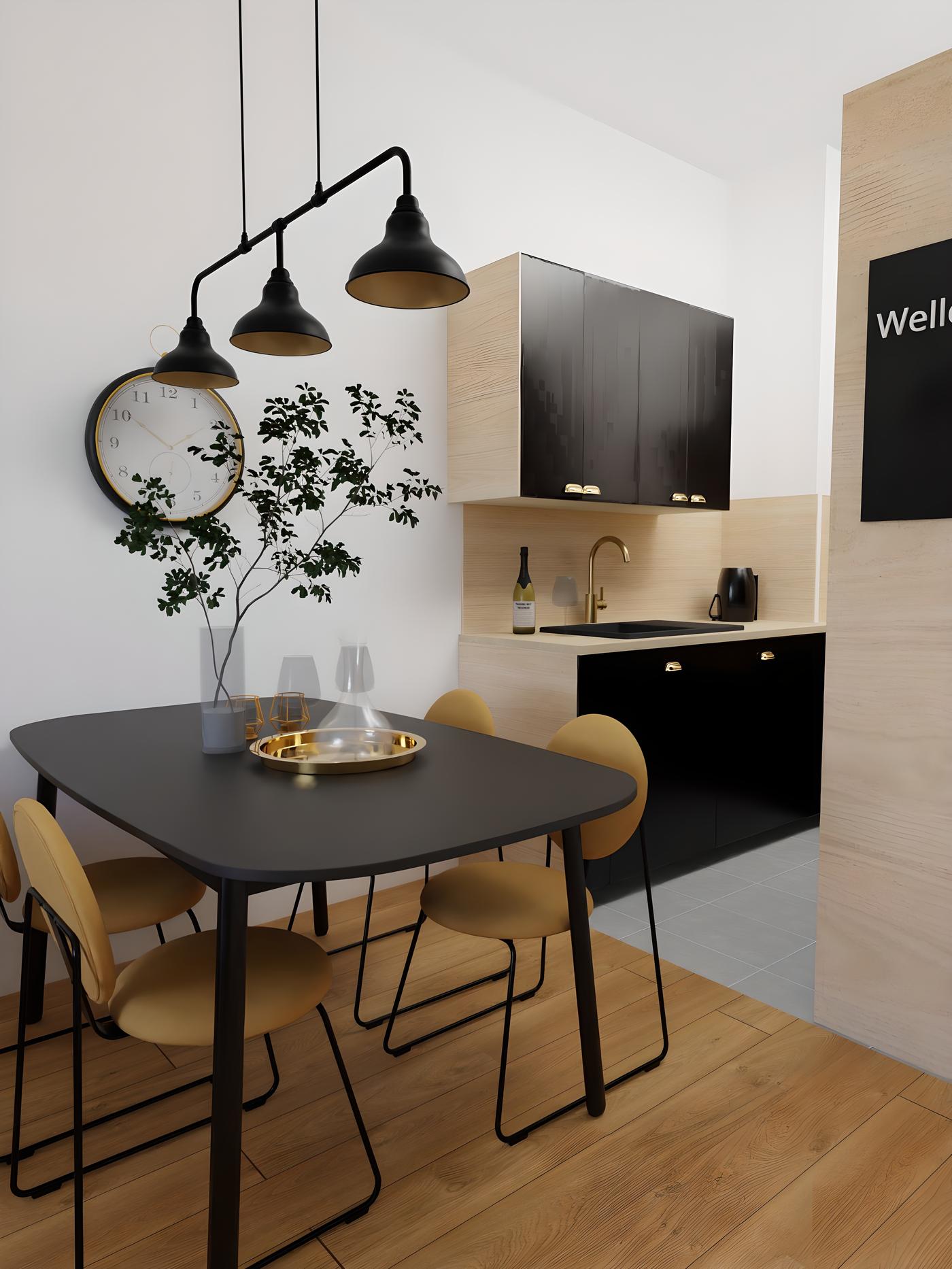 Moderna kuhinja s crnim ormarićima, stolom i stolicama, zlatnim detaljima i zidnim satom. Na stolu je pladanj s čašama i vaza s grančicama.