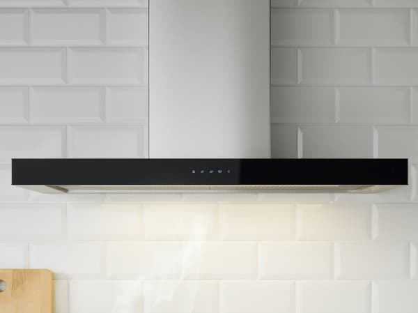 Moderne Dunstabzugshaube mit schwarzem Design, montiert an einer weiß gefliesten Wand; auf der Vorderseite sind Bedientasten sichtbar.