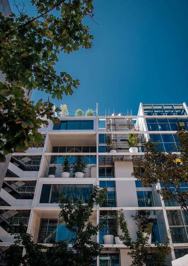Moderne Gebäudefassade mit üppiger Bepflanzung in weißen Töpfen – nachhaltige Architektur von IKEA in Wien.