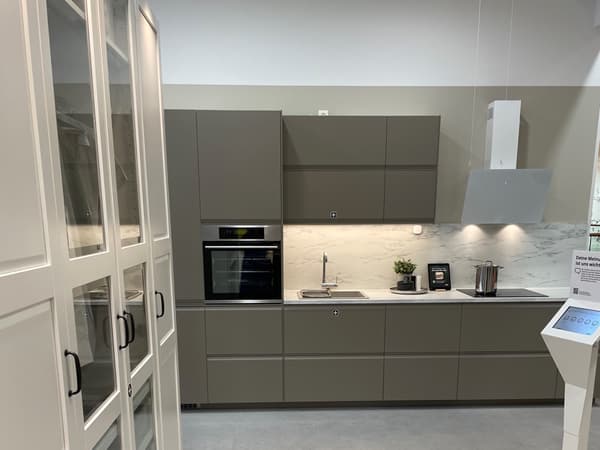 Moderne IKEA Küchenzeile in mattem Grau mit Marmor-Rückwand und weißen Oberschränken.